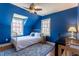 Stylish blue bedroom features a bed with bright windows, ceiling fan, hardwood floors, and a comfortable workstation at 1010 Rosehill Ave, Durham, NC 27705