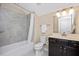 Clean bathroom with a tub-shower combo, dark vanity, and neutral tiling at 1013 Restoration Dr, Durham, NC 27703