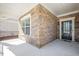 Close-up of home exterior with stone siding, covered porch, and black front door with glass panels at 1013 Restoration Dr, Durham, NC 27703