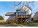 A tiered wooden deck is supported by a wooden frame on a light blue house with a dark roof at 104 Stenness Ct, Apex, NC 27502