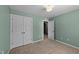 This bedroom has neutral carpet and walls, with a closet and door at 104 Vinewood Pl, Holly Springs, NC 27540