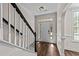 Bright entryway with hardwood floors, white trim, and a staircase with black handrail at 104 Vinewood Pl, Holly Springs, NC 27540