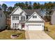 Charming two-story home with gray siding, black shutters, and a well-manicured front yard with an American flag at 104 Vinewood Pl, Holly Springs, NC 27540