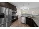 Bright kitchen featuring stainless steel appliances, granite countertops, and dark cabinetry at 104 Vinewood Pl, Holly Springs, NC 27540