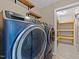 This laundry room features a pair of blue GE washer and dryer with door to storage room at 104 Vinewood Pl, Holly Springs, NC 27540
