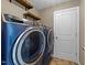 This laundry room features a pair of blue GE washer and dryer and wooden shelving at 104 Vinewood Pl, Holly Springs, NC 27540