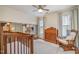 A well-lit Bedroom with wood crib, ceiling fan, a book shelf, and neutral tones at 1044 S Philwood Ct, Fuquay Varina, NC 27526