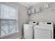 Bright laundry room with a window, modern washer and dryer, and storage space at 127 Station Dr, Morrisville, NC 27560