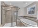Bright bathroom featuring a tiled shower with glass doors, soaking tub, and a large window at 1416 Endgame Ct, Wake Forest, NC 27587