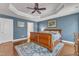 Comfortable main bedroom featuring beautiful blue walls, hardwood floors, and a tray ceiling with a ceiling fan at 1416 Endgame Ct, Wake Forest, NC 27587