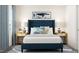 Cozy bedroom with a blue upholstered bed, decorative pillows, and matching nightstands with elegant lamps at 1755 Barrett Run Trl # 213, Apex, NC 27502