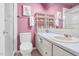 A pink bathroom featuring a toilet, sink, vanity, mirror, shelves, and shower-tub combo at 198 Ridge Trl, Chapel Hill, NC 27516