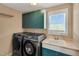 Laundry room with green cabinets, front loading washer and dryer, and white utility sink at 2015 Stanchion St, Haw River, NC 27258
