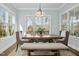 Sunlit dining room featuring a wooden table, upholstered chairs, bench and large windows with backyard view at 2046 Fellini Dr, Apex, NC 27502