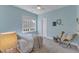 Light blue bedroom with a cozy chair, textured carpet, and natural light at 205 Virginia Water Dr, Rolesville, NC 27571