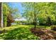 Expansive backyard with lush green lawn and mature trees, leading to a serene lakefront setting at 2140 N Lakeshore Dr, Chapel Hill, NC 27514