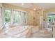Well-lit bathroom with walk-in shower, soaking tub under large windows, and natural stone tile at 2140 N Lakeshore Dr, Chapel Hill, NC 27514