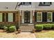 Elegant brick entrance with black shutters, a charming portico, and well-maintained landscaping at 2140 N Lakeshore Dr, Chapel Hill, NC 27514