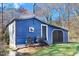 Side view of a blue shed with a black door and a cardinal painting on the wall at 2246 Arrowhead Rd, Dunn, NC 28334