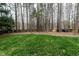 Spacious backyard with lush green grass, bordered by mature trees and a wooden fence at 2301 Lemuel Dr, Raleigh, NC 27615