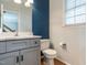 Cozy bathroom with modern gray vanity, white quartz countertop, blue accent wall, and hardwood floors at 2301 Lemuel Dr, Raleigh, NC 27615