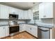 Modern kitchen featuring white cabinets, stainless steel appliances, granite countertops, and hardwood floors at 2301 Lemuel Dr, Raleigh, NC 27615