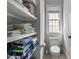 Bright bathroom with a toilet and open shelving holding neatly folded towels at 233 Candia Ln, Cary, NC 27519