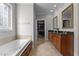 Bright bathroom with a soaking tub, wood cabinets, granite counters, framed mirrors, and access to a walk-in closet at 233 Candia Ln, Cary, NC 27519