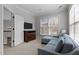 Bright bedroom with a plush blue chaise lounge, mounted TV, a neutral carpet, and natural light from a window at 233 Candia Ln, Cary, NC 27519