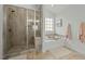 Bathroom featuring a glass-enclosed shower, a soaking tub beneath a window, and tiled walls and floors at 234 Macallan Dr, Burlington, NC 27215
