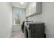 Laundry room featuring modern washer and dryer units, bright window, and upper cabinets at 234 Macallan Dr, Burlington, NC 27215