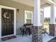 Inviting front porch with brick-based columns, comfortable seating, and a festive wreath on the door at 2575 Sheriff Watson Rd, Sanford, NC 27332