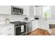 Bright kitchen featuring stainless steel appliances, white cabinets and countertops, and wood flooring at 2816 Cascadilla St, Durham, NC 27704