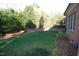 Lush backyard with manicured lawn, mature trees, and a brick retaining wall at 3204 Cobblestone Ct, Raleigh, NC 27607
