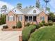 Beautiful brick home featuring a charming front porch with rocking chairs and lush landscaping at 3204 Cobblestone Ct, Raleigh, NC 27607