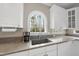 Bright kitchen showcases granite countertops, a stainless steel sink below an arched window, and ample storage with white cabinets at 3312 Clandon Park Dr, Raleigh, NC 27613