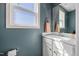 Bathroom with white vanity, white framed window, and teal colored walls at 38 Winter Red Way, Benson, NC 27504