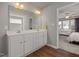Bathroom with a double vanity with white cabinets, large mirror, and wood floors at 38 Winter Red Way, Benson, NC 27504