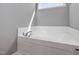 A modern white bathtub with chrome fixtures and sunlight streaming through the window at 38 Winter Red Way, Benson, NC 27504