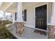 Inviting front porch with stone-wrapped posts, a black front door, and a cozy 