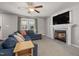 Inviting living room featuring a stone fireplace, a ceiling fan, and comfortable blue seating at 38 Winter Red Way, Benson, NC 27504