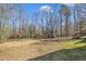 Large, grassy backyard perfect for recreation, surrounded by a border of mature trees and a glimpse of the home at 484 Galaxy Dr, Garner, NC 27529