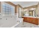 Bright bathroom with a large soaking tub, marble tile floors, dual sink vanity, and glass block window at 484 Galaxy Dr, Garner, NC 27529