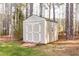 Outdoor storage shed with double doors and a small window, nestled amongst mature trees at 50 Lockamy Ln, Youngsville, NC 27596