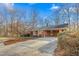 A single story home featuring a paved driveway leading to a charming brick home in a wooded setting at 501 Orange High School Rd, Hillsborough, NC 27278