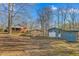 Property featuring a brick house, blue garage, and car shelter on a wooded lot at 501 Orange High School Rd, Hillsborough, NC 27278