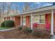 Inviting covered front porch with red chairs, complemented by red shutters and landscaped greenery at 501 Orange High School Rd, Hillsborough, NC 27278