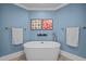 A standalone tub is featured in a blue toned bathroom with tile flooring and contemporary decor at 513 N Nash St, Hillsborough, NC 27278
