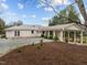 Wide driveway leads to a white brick house with a covered entrance, featuring a mix of textures and plantings at 513 N Nash St, Hillsborough, NC 27278