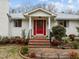 Close up image of white brick home featuring a red front door with meticulously landscaped front yard at 513 N Nash St, Hillsborough, NC 27278